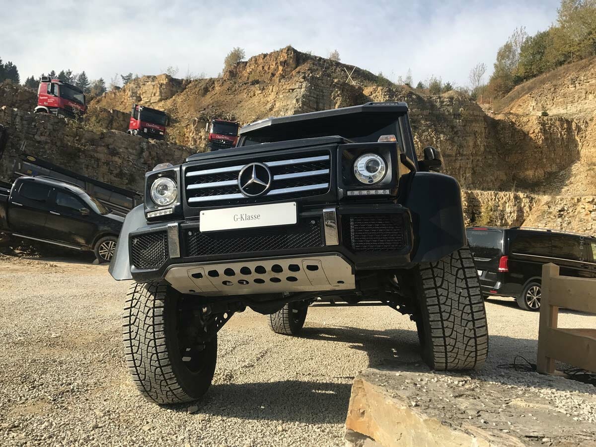 Un fuoristrada nero si trova con una gomma su una pietra in un ambiente sabbioso.