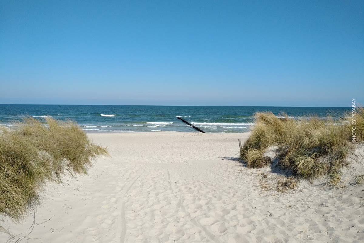 Un sentiero di sabbia porta alla spiaggia e al mare