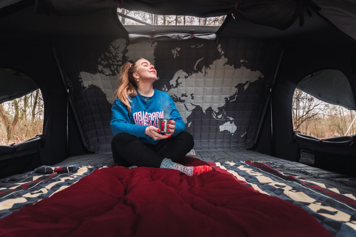 Donna rilassata con una tazza di tè nella sua tenda da tetto per Toyota Hilux