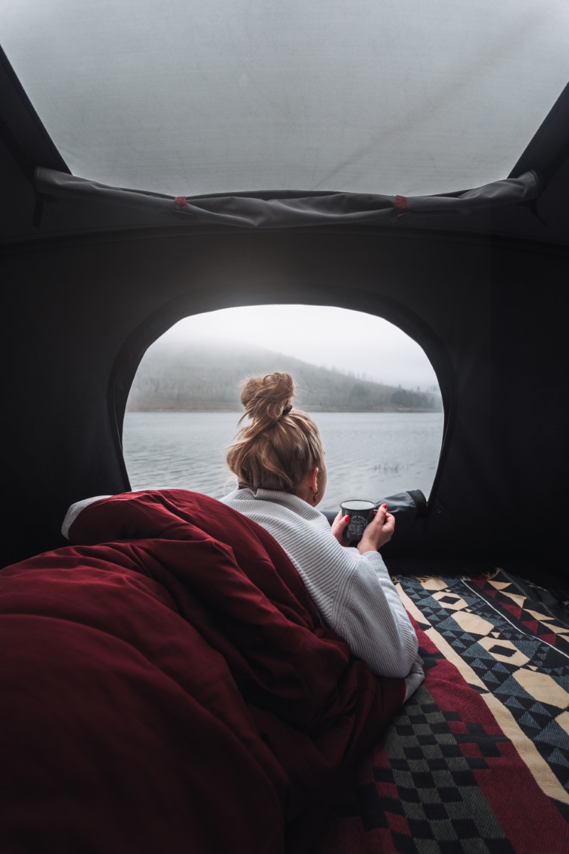 Donna si gode una tazza di tè in tenda da tetto sul T6