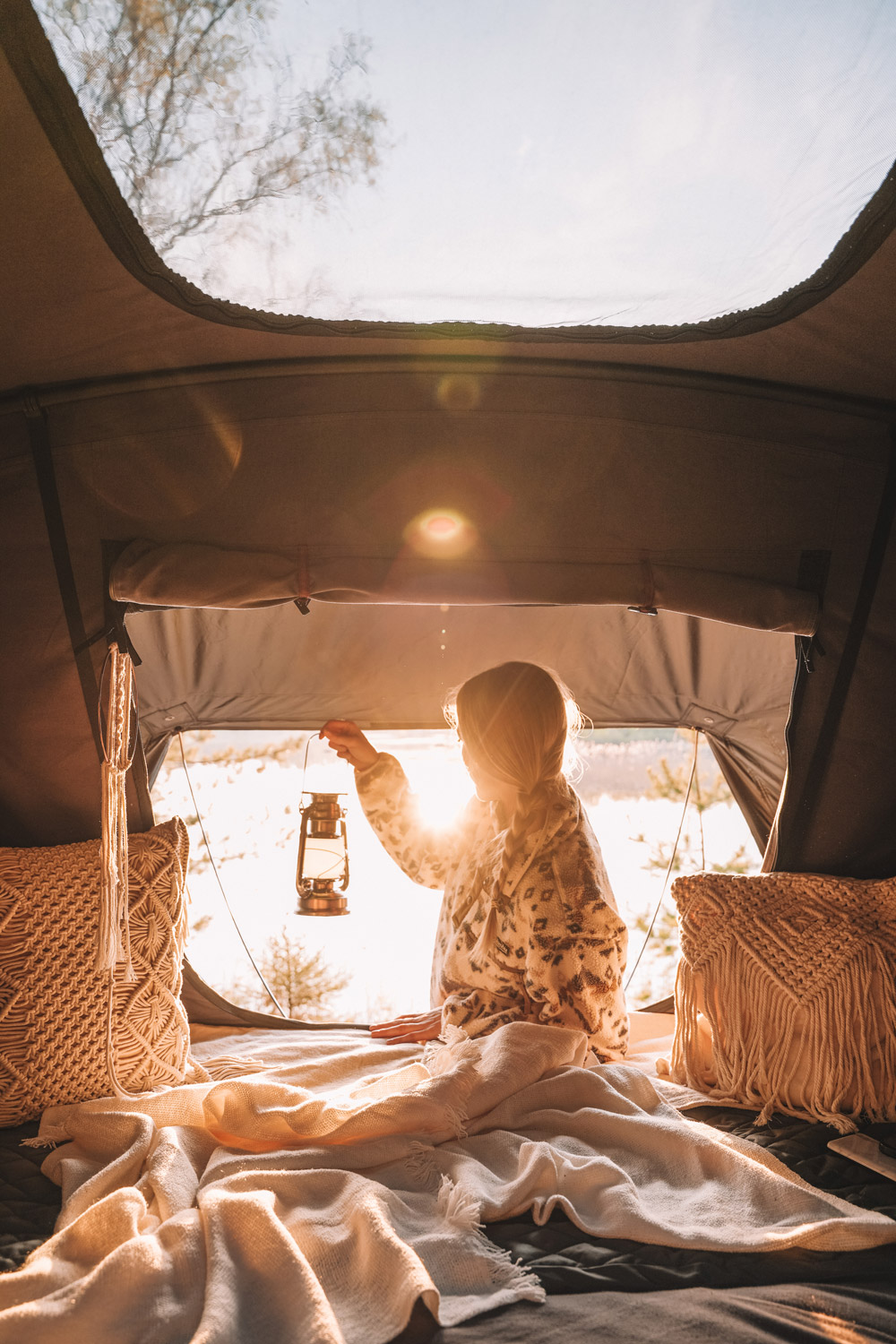 Donna guarda al crepuscolo dall'apertura della sua tenda da tetto